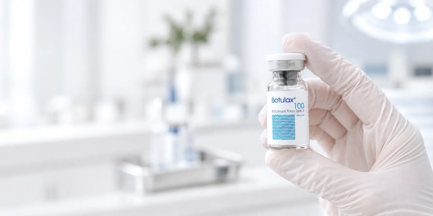 Gloved hand holding a Botulax 100 unit vial in a clinic