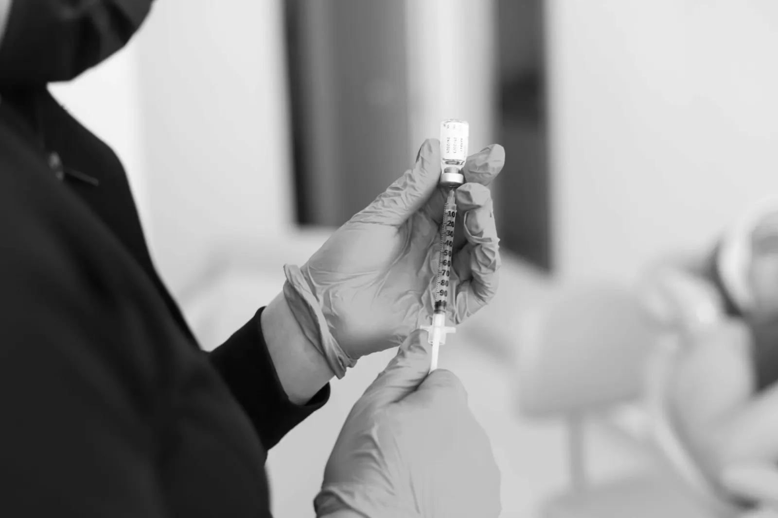 Clinician in gloves drawing botulinum toxin from a vial into a syringe